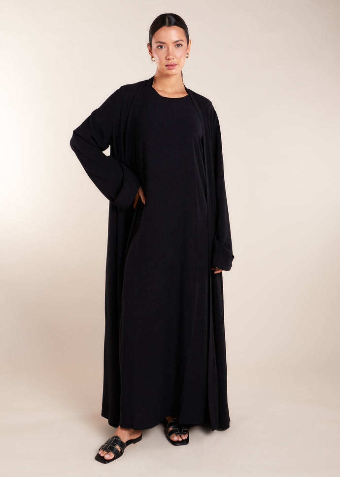 This elegant Two Piece Open Abaya set includes a Full Sleeve matching inner dress. Perfect for everyday wear, it can also be dressed up with accessories for an evening look. The open abaya can be worn as a maxi on its own or paired with the inner dress for a stylish ensemble. In black.